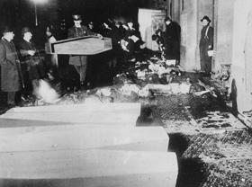 Policemen line up coffins on the sidewalk next to the bodies of victims that wait to be transported to the morgue