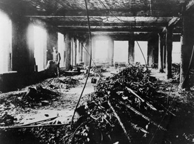 Policeman stands in a burnt out window on the 9th floor of the Asch Building